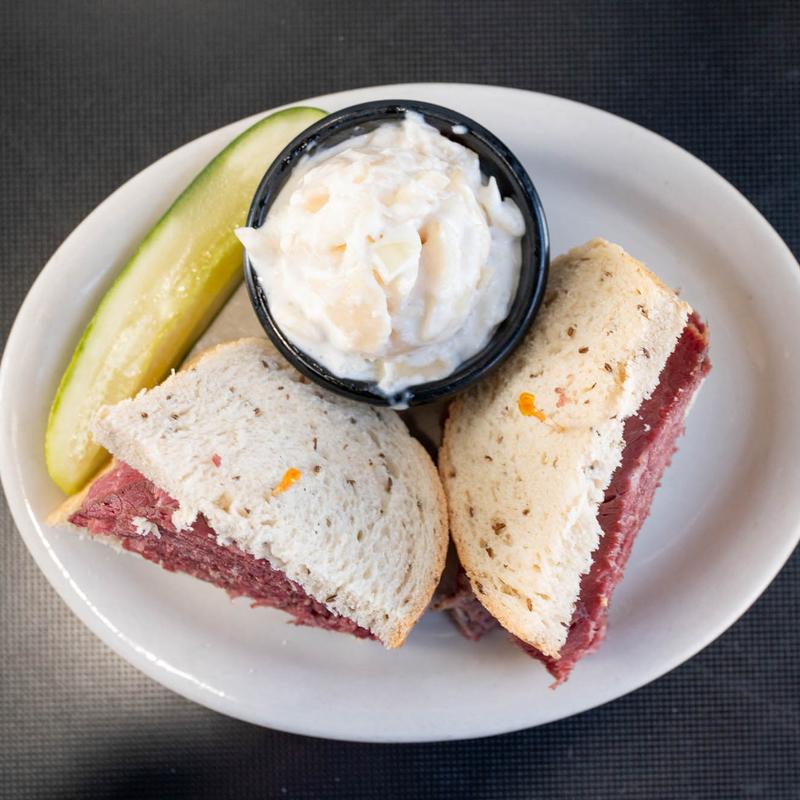 Lester's hot corned beef sandwich on rye with a pickle and potato salad